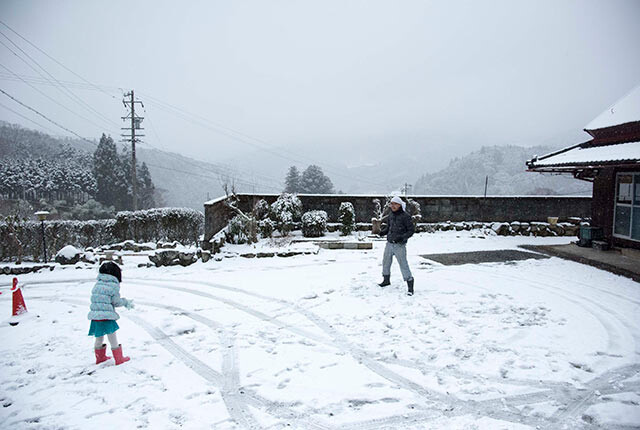 庭で雪で遊ぶ津留崎さんの夫と娘さん
