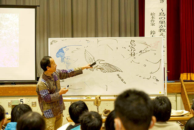 鈴木さんがホワイトボードにウミネコの絵を描いている