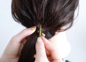 ピンを閉じた状態で端が短い部分を下にし、ゴムに巻き付けた毛束の表面と毛先を合わせてピンですくいます。地肌に対してピンが垂直になるように押し込んでいきます