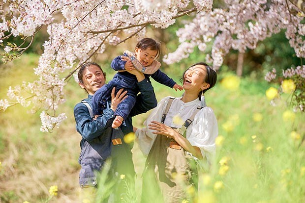 桜満開の中で笑顔をみせる、畠山千春さん、ご主人のコーイチさん、娘さんのショット