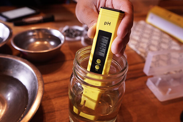 pHチェッカーで灰洗剤のpH値を計っている写真。表示されている数値は「pH14」