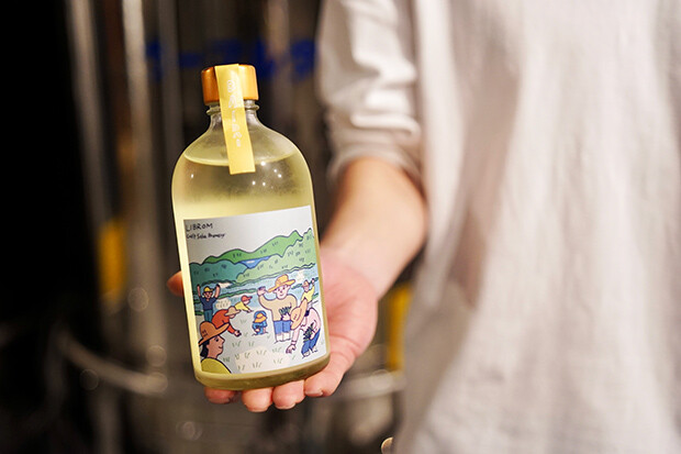 田植えをする人々がポップなイラストで描かれたラベルのお酒のボトル写真。