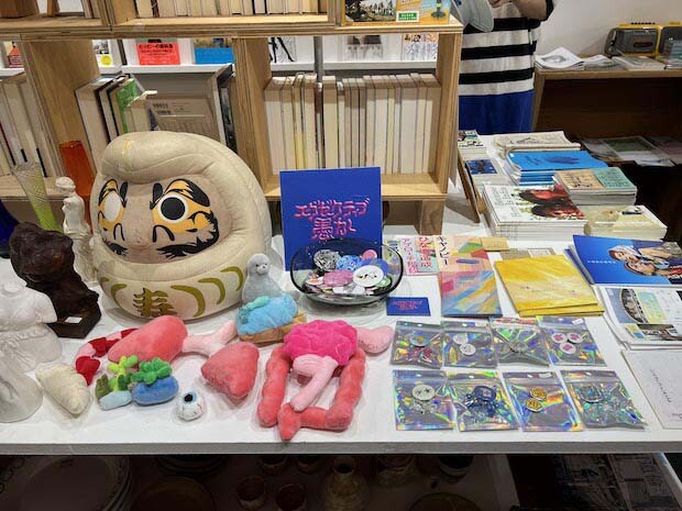 「エグゼクティブ愚か」のぬいぐるみや缶バッジ。
