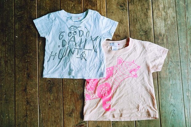 今回草木染を行う、白地に文字イラストが入った子ども用Tシャツと、ピンク地にイヌのようなイラストが描かれた子ども用Tシャツが並んだ写真。