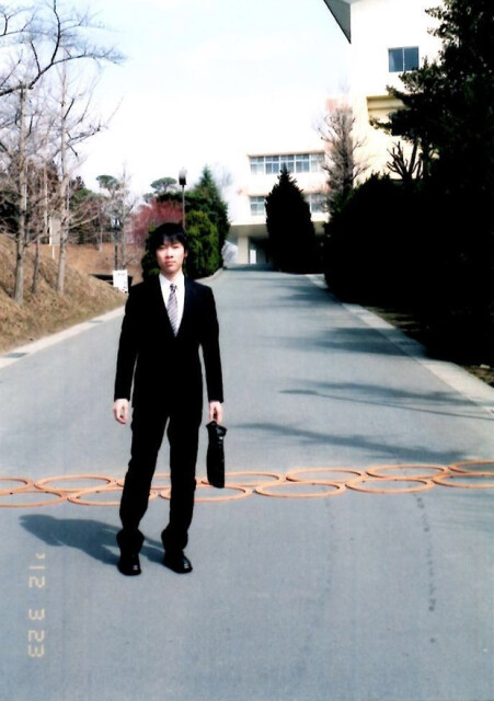 高校卒業直後に校門にて撮影した及川さんの写真。