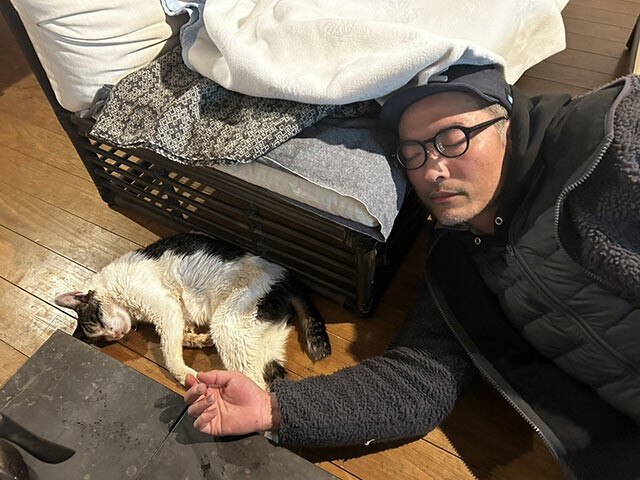 自宅のソファで寝落ちした津留崎さん。隣では猫のコロンさんも寝ている